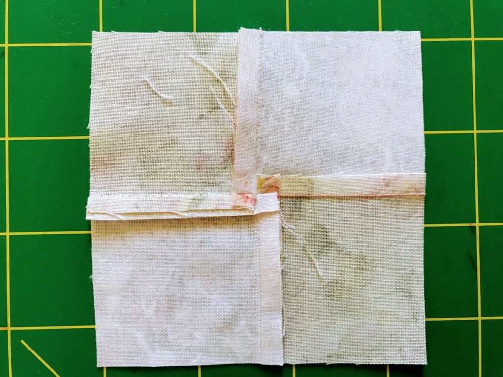 A Four Patch quilt block with a twirled center seam
