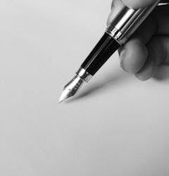 Black and silver fountain pen writing on white paper, close-up shot.