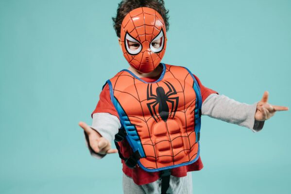 Child wearing a Spiderman costume and mask striking a playful superhero pose in a studio setting. Photo by Pavel Danilyuk