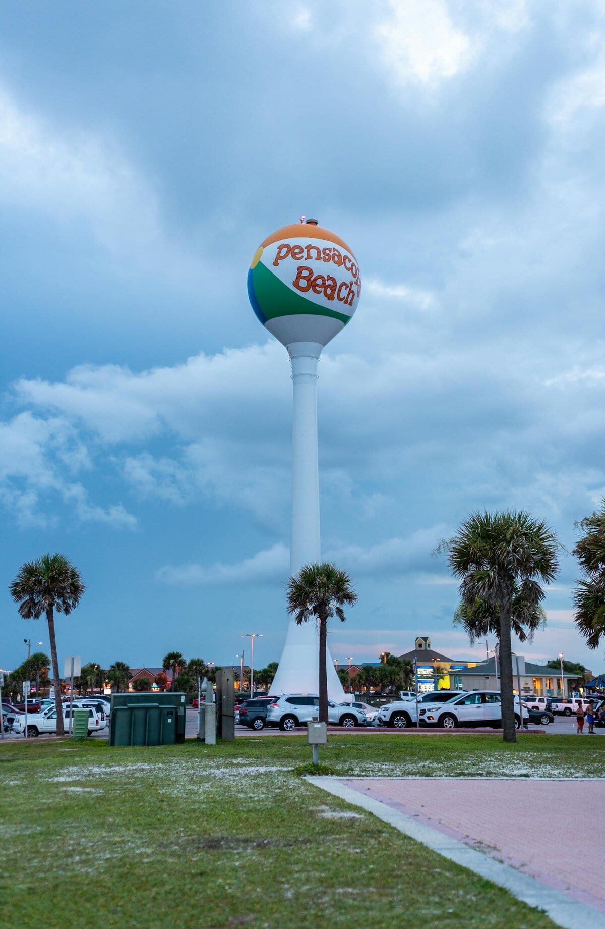 Scenic view of the iconic Pensacola Beach water tower with palm trees and cloudy sky by Dominik Gryzbon