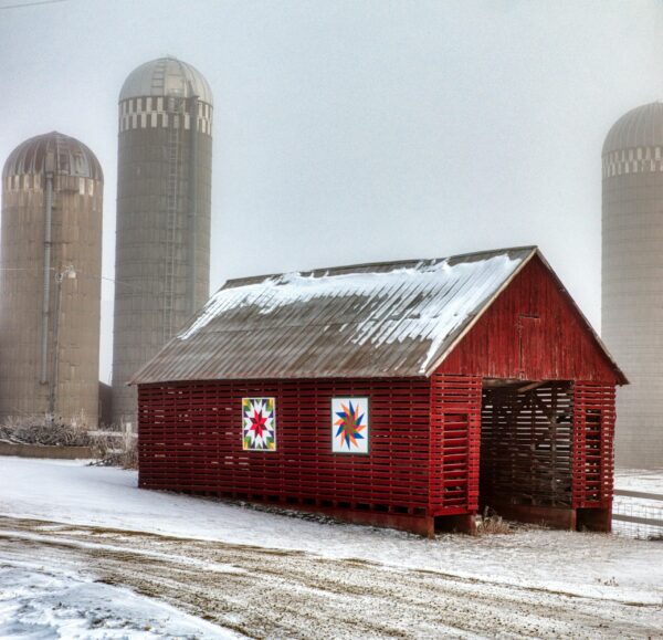 Snow-covered red barn with silos in wintry rural Minnesota landscape by Tom Fisk