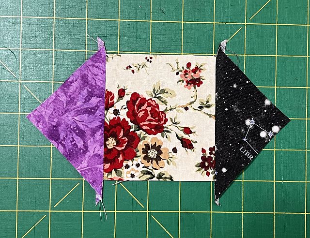 Scrapdash fabric scrap pieces with floral, galaxy, and purple patterns on green cutting mat, quilting and sewing project materials.