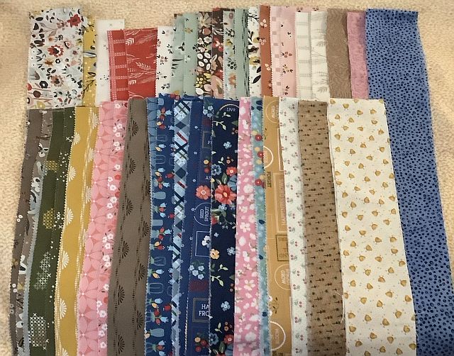 Rows of colorful fabric strips with various patterns, including florals, polka dots, geometric shapes, and fruit prints, neatly arranged side by side on a light surface.