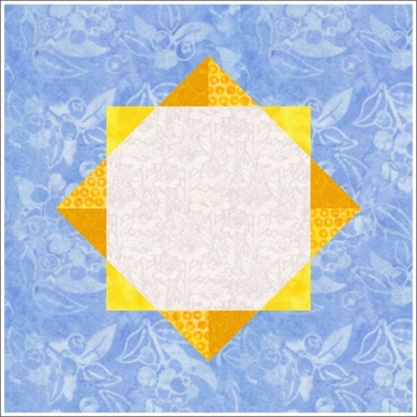 A quilt block features a white central square patterned with flowers, surrounded by yellow and orange triangles forming a star, set against a blue floral background.